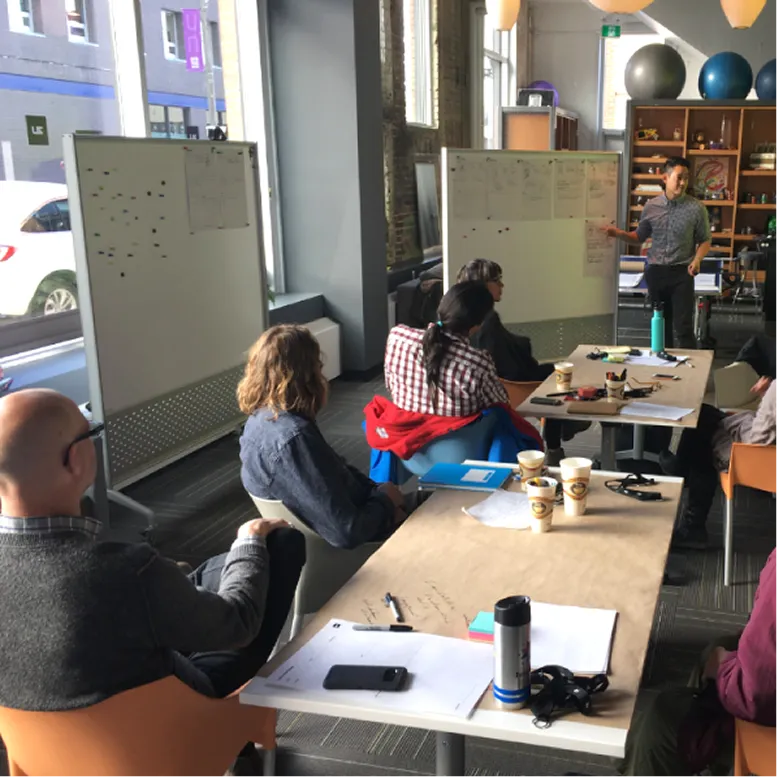 Designer sketching interface wireframes and notes on a glass wall