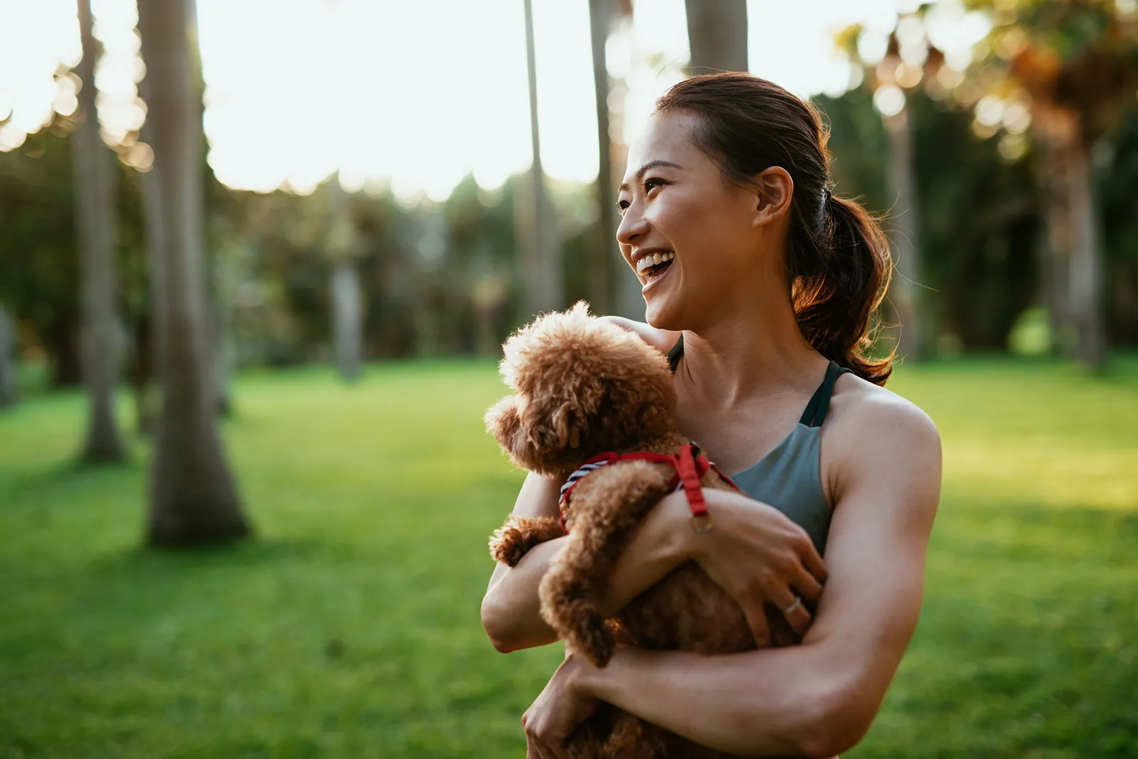Smiling woman holding a small dog in a park